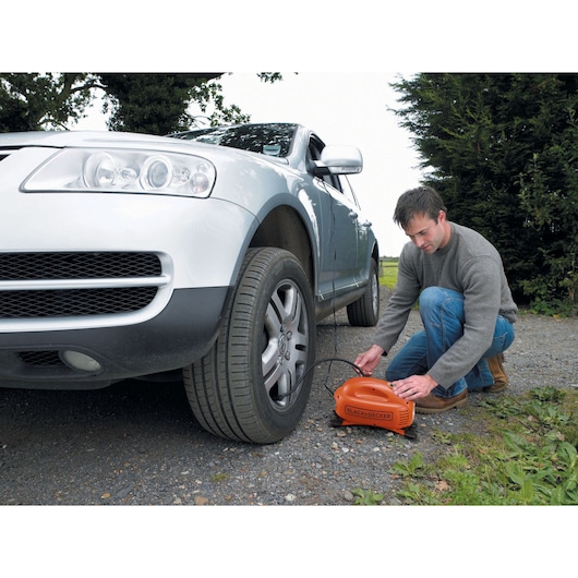 BLACKDECKER ASI200 orange portable air compressor inflating car tire outdoors