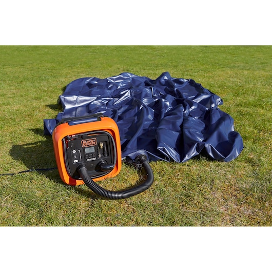BLACK+DECKER ASI400 portable air compressor inflating a blue air mattress on grass.