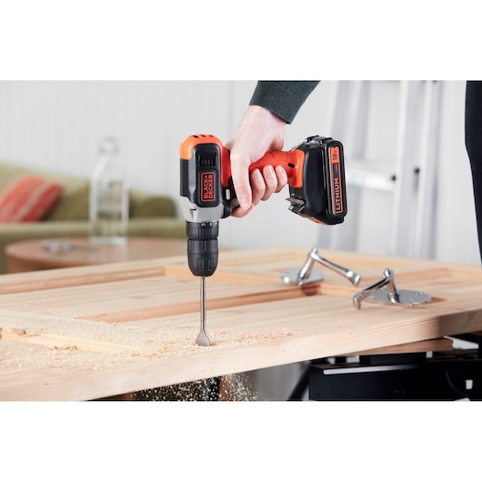 Photo of BLACK+DECKER cordless drill BCD001C2 in use drilling wood, close-up angle.