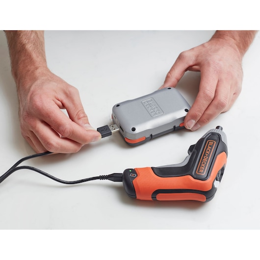 Photo of BLACK+DECKER BCF611CK cordless screwdriver charging via USB cable connected to a silver power bank.