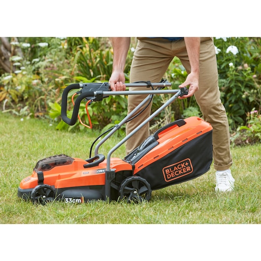 Photo of BLACKDECKER BCMW33184L2 lawn mower with orange and black design in use on grass.
