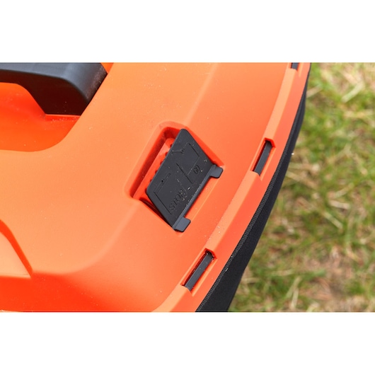 Close-up photo of BLACKDECKER BCMW33185L2 lawn mower control panel with black stop button on orange body.