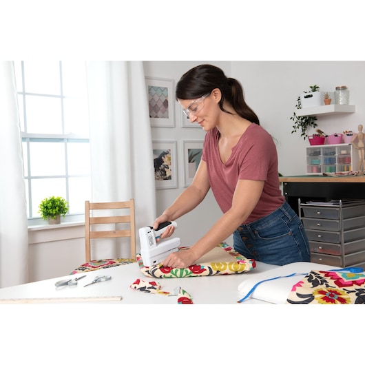 BLACKDECKER BCN115 stapler used to upholster floral fabric on table in creative workspace.