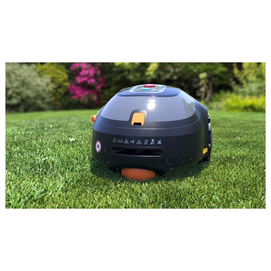 BLACKDECKER BCRMW121 robotic lawn mower on grass, rear view with orange details, garden background.
