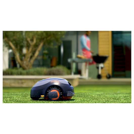 BLACKDECKER BCRMW121 robotic lawn mower on grass in a garden setting, side view.