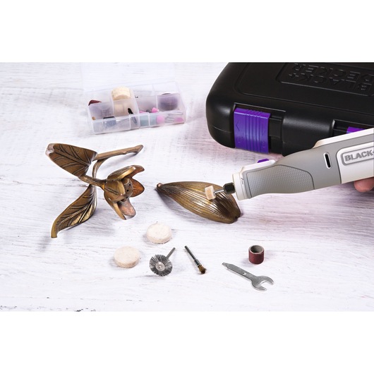 BLACK+DECKER BCRT8IPETK rotary tool polishing metal flower with accessory bits and carrying case.