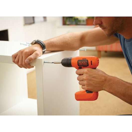 BLACKDECKER BDCD8 cordless drill used to assemble white furniture indoors.