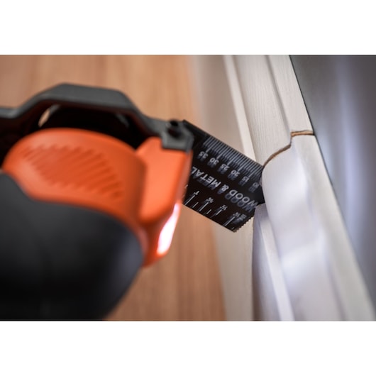 BLACKDECKER BDCOS18N oscillating multi-tool cutting white trim with black metal blade, close-up view.