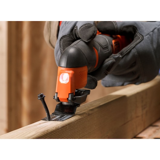 BLACKDECKER BDCOS18N oscillating multi tool cutting wood, close-up with gloved hand, construction setting.