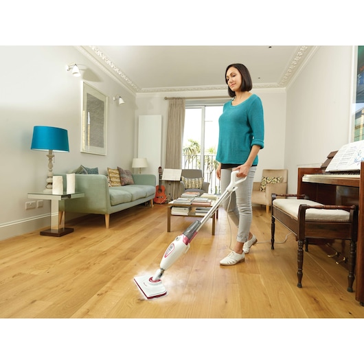BLACKDECKER BDS1616R steam mop cleaning wooden floor in living room, person standing and using product.
