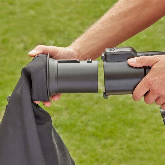 BLACKDECKER BEBLV260 leaf blower close-up attaching black collection bag outdoors.
