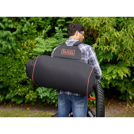 BLACKDECKER BEBLV301 leaf vacuum bag worn on back, black with orange trim, garden background.