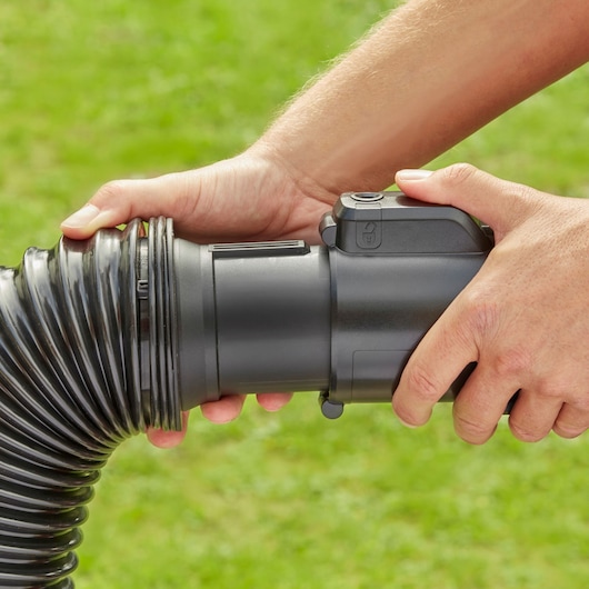 Photo of BLACKDECKER BEBLV301 hose attachment being connected by hand outdoors.