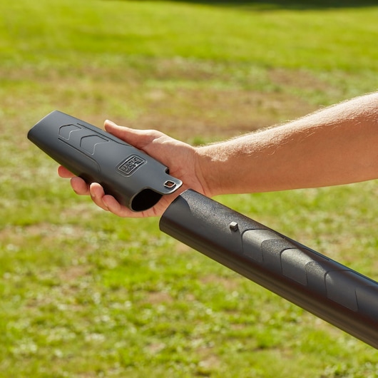 Photo of BLACKDECKER BEBLV301 blower tube attachment held outdoors, black plastic with logo visible.