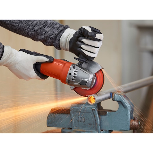 BLACKDECKER BEG110K angle grinder cutting metal pipe, held in vise, operator wearing gloves.