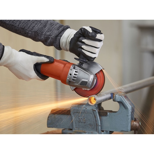 Photo of BLACKDECKER BEG110 angle grinder cutting metal pipe with sparks flying.