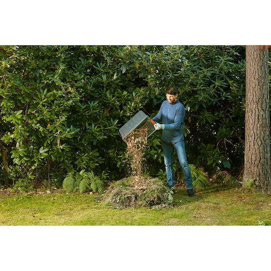 BLACKDECKER BEGAS5800 garden shredder, person emptying shredded material onto a compost pile outdoors.