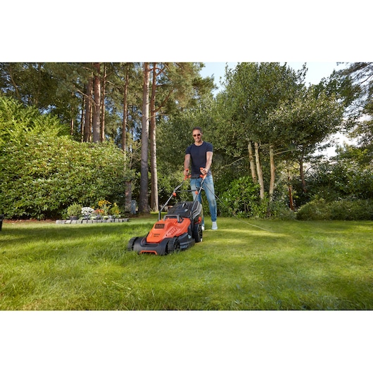BLACKDECKER BEMW471BH electric lawn mower in use on a grassy lawn, orange and black design.