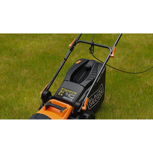 BLACK+DECKER BEMWP340-QS electric lawn mower close-up on grass, showing handle and safety labels.