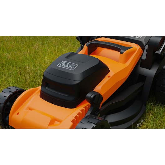 Close-up of BLACK+DECKER BEMWP340-QS orange and black lawn mower on green grass.