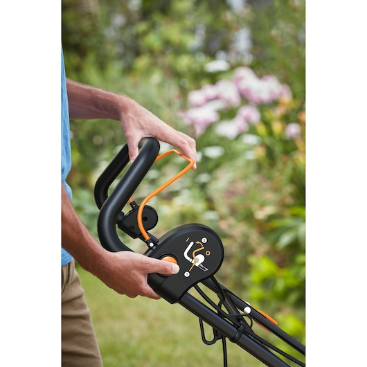 BLACKDECKER BEMWP340-QS lawn mower handle closeup, showing control panel and orange safety lever outdoors.
