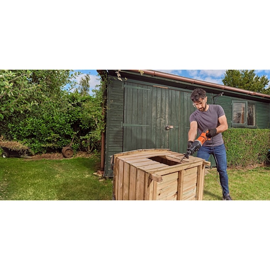 BLACKDECKER BES301K reciprocating saw used outdoors on wooden crate by person in gloves.