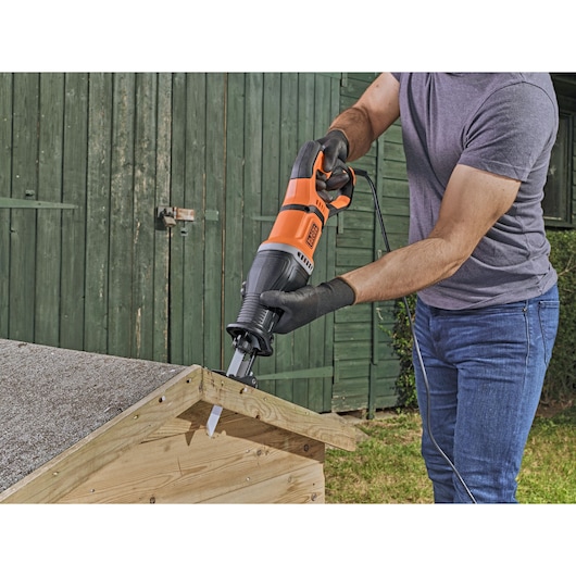 Photo of BLACKDECKER BES301K reciprocating saw in use for cutting wood outdoors.