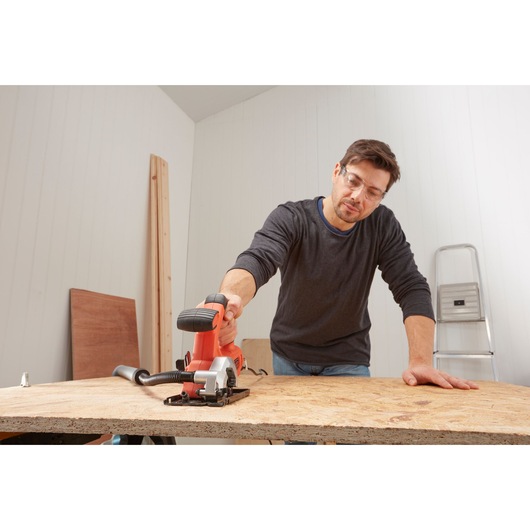 BLACKDECKER BES510K compact circular saw used on wood panel in workshop setting.