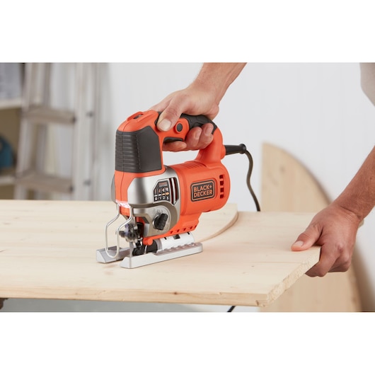 BLACK+DECKER BES610 jigsaw cutting wood, close-up of tool in use.