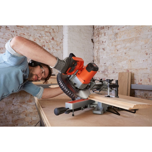 BLACKDECKER BES700 miter saw in use on woodwork table, cutting wooden board, indoor workshop.
