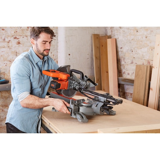 BLACKDECKER BES700 miter saw in use on a workbench, orange and gray design, woodworking setting.