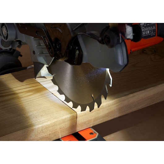 BLACKDECKER BES702 miter saw blade close-up cutting wooden board, side angle.