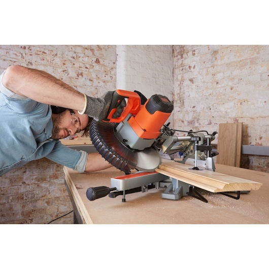 BLACKDECKER BES710 miter saw in use cutting wood plank on workbench in workshop.