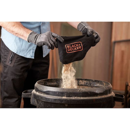 BLACKDECKER BES710 dust bag emptied into a bin, close-up of product and gloves.