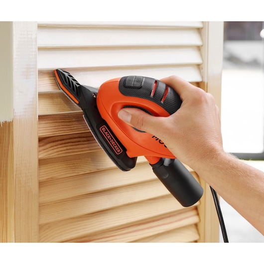 BLACKDECKER BEW230BCA hand sander in use on wooden blinds, close-up photography.
