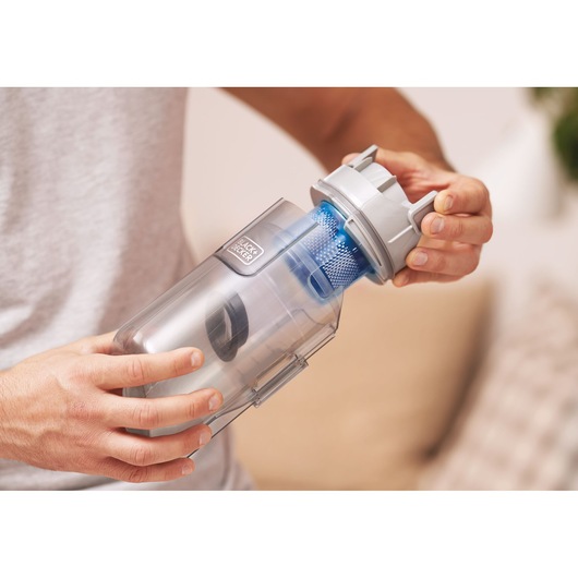 Photo of BLACK+DECKER BHFEA420J vacuum cleaner dust container being opened by hand, silver and blue plastic design.