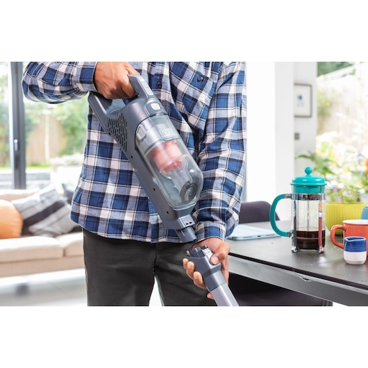 Photo of BLACKDECKER BHFEA520J cordless vacuum cleaner in use, person attaching nozzle in modern living room.
