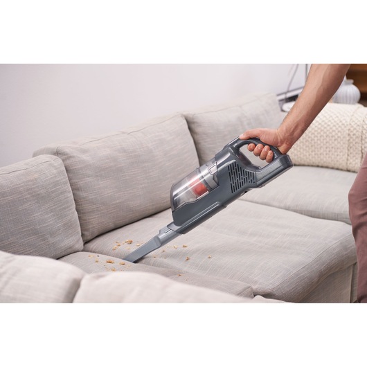 BLACKDECKER BHFEA520J handheld vacuum cleaner cleaning crumbs from a light gray sofa.