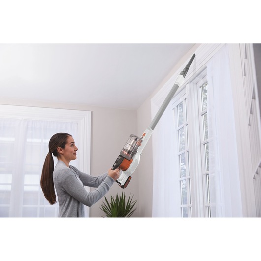 Photo of BLACKDECKER BHFEV1825C vacuum cleaner used to clean high corners near a window indoors.