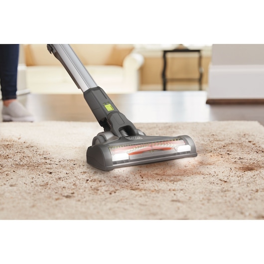 BLACKDECKER BHFEV362DA cordless vacuum cleaning dirty carpet in a bright living room.