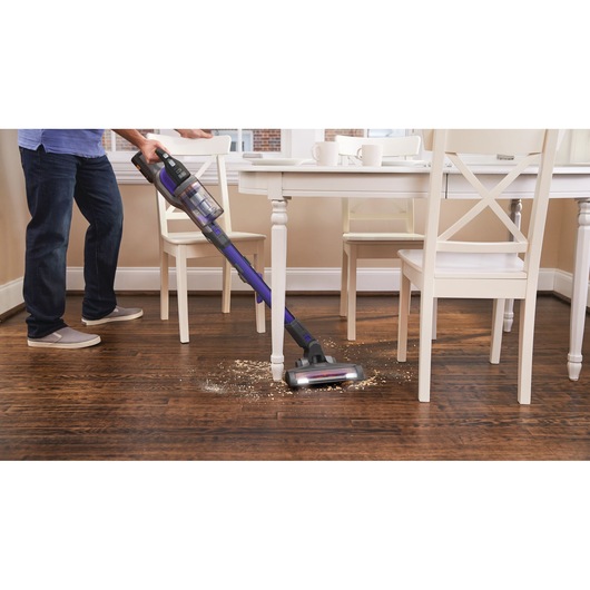 BLACKDECKER BHFEV362DP stick vacuum cleaning debris from hardwood floor near dining table.