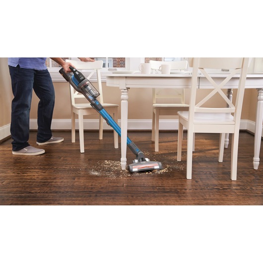 BLACKDECKER BHFEV362D cordless stick vacuum cleaning debris on hardwood floor in kitchen.