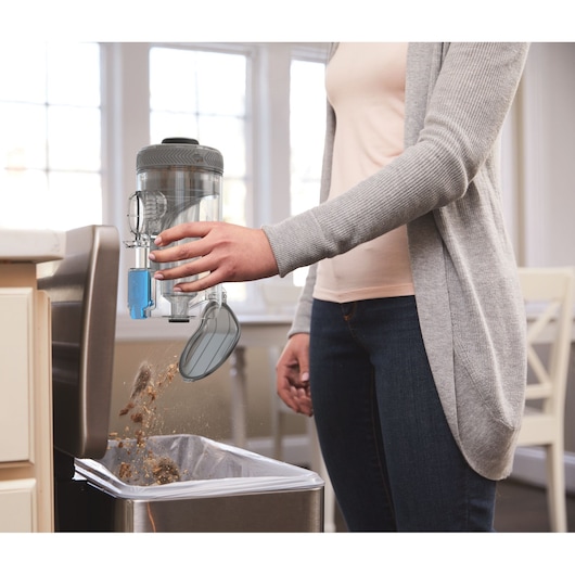 BLACKDECKER BHFEV362D vacuum dustbin being emptied into a kitchen trash can.