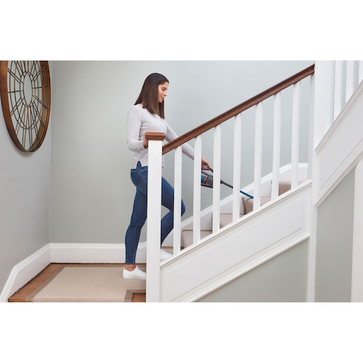 BLACKDECKER BHHV320B handheld vacuum cleaning stairs in a modern home interior.