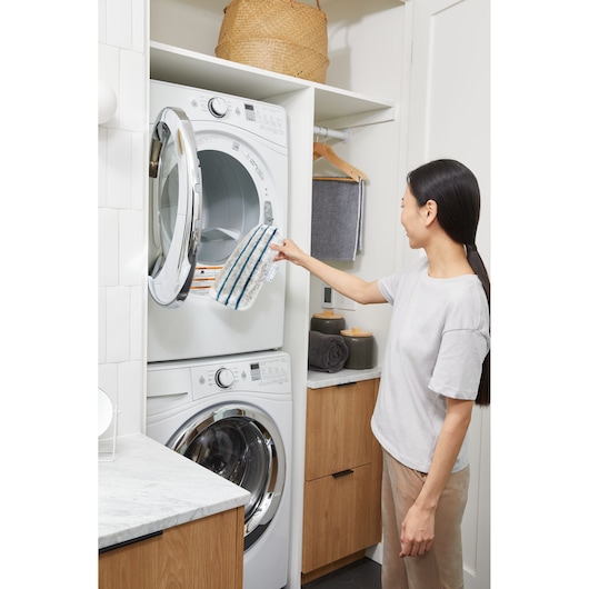BLACKDECKER BHSM15FX08 mop pad held by person near stacked washer and dryer in laundry room.