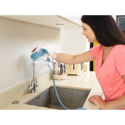 BLACKDECKER BHSM1615DSM steam cleaner used on kitchen faucet, flexible blue hose, modern countertop.
