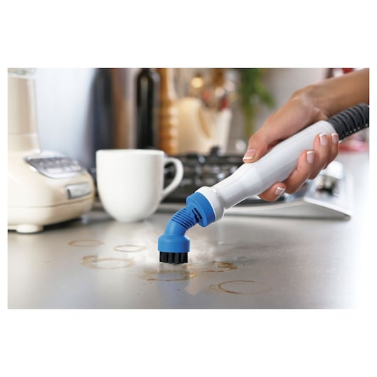 BLACKDECKER BHSM1615DSM handheld cleaner with blue brush attachment cleaning countertop stains.