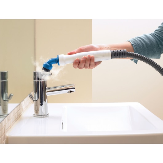 BLACKDECKER BHSM168D handheld steam cleaner cleaning bathroom faucet with steam, close-up view.