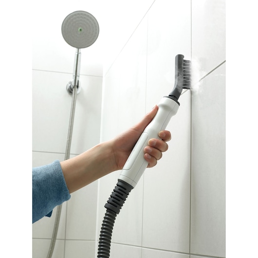 BLACKDECKER BHSM168D steam cleaner cleaning shower tile grout with grey brush attachment, handheld close-up.