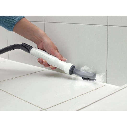 BLACKDECKER BHSM168D steam cleaner with brush attachment cleaning tile grout in a bathroom, perspective close-up.